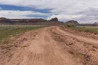 a dirt road through an arid landscape with mountains in the distance under a blue sky