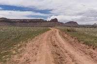 a dirt road through an arid landscape with mountains in the distance under a blue sky