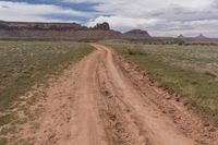 a dirt road through an arid landscape with mountains in the distance under a blue sky