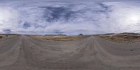 a 360 view of an empty dirt road in the middle of nowhere under cloudy skies