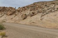 a motorcycle is going down a dirt road in the mountains in the desert in arizona