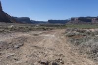 a dirt road with mountains in the background in a desert area at the bottom of the image