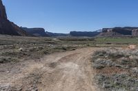 a dirt road with mountains in the background in a desert area at the bottom of the image