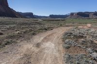 a dirt road with mountains in the background in a desert area at the bottom of the image