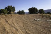 a large dirt road with trees on the side of it and mountains in the distance