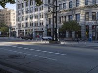 two cars are driving down the street, in front of tall buildings, on an intersection