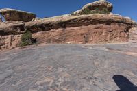 the man is taking a picture on a rock face down at arches rock formation in canyon district of moabd