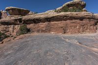 the man is taking a picture on a rock face down at arches rock formation in canyon district of moabd