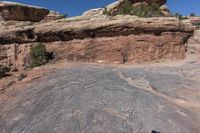 the man is taking a picture on a rock face down at arches rock formation in canyon district of moabd