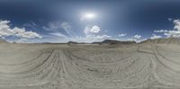 an empty dirt area with rocks, sand and clouds in the sky and sun shine in the horizon