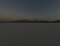 a field is empty with a lot of snow on it and mountains in the distance