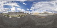 the two cars are driving down the road towards the mountain tops in this panorama photo