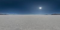 a panorama view of an expanse with mountains and snow in the distance on a sunny day