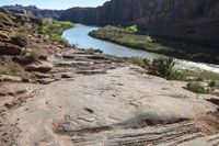 a person is standing on top of the rock ledge over looking the river in the distance