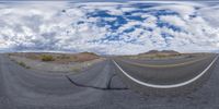 an empty road in the middle of nowhere with two yellow lines and a cloudy sky