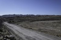 gravel road on a rocky field near a mountain range and distant landscape, in the middle of the day