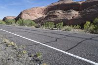 a highway runs through the middle of an arid terrain with sparse vegetation on both sides and large, jagged hills near the top of the road