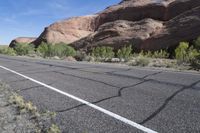 a highway runs through the middle of an arid terrain with sparse vegetation on both sides and large, jagged hills near the top of the road