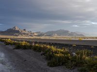 a empty highway with mountains in the background on the horizon at dusk with a sky filled with clouds