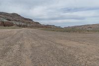 an empty field next to a big mountain with rocks in the background of the picture