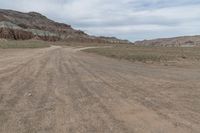 an empty field next to a big mountain with rocks in the background of the picture