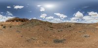 a panorama of the desert with lots of vegetation on it and mountain under cloudy skies