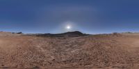 a view of a sky and some mountains from a fish eye lensed image shows a barren hill on top