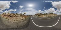 a very wide 360 - lens view of a desert road and road side sign with clouds in the sky