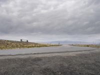 there is an empty road going into a rural area on a cloudy day with the sun