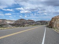 a street has yellow double lines on it and an area of rocky landscape is in the background