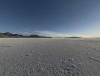 a lone man walking in the middle of an empty, barren plain covered with snow