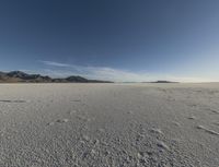 a lone man walking in the middle of an empty, barren plain covered with snow