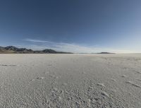 a lone man walking in the middle of an empty, barren plain covered with snow