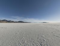 a lone man walking in the middle of an empty, barren plain covered with snow