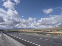 a large highway leads into the mountains with snow capped peaks in the background on a clear day