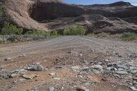 an empty dirt road on the side of the mountain with some rocks in the foreground