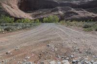 an empty dirt road on the side of the mountain with some rocks in the foreground