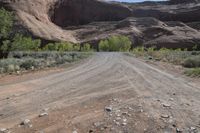 an empty dirt road on the side of the mountain with some rocks in the foreground