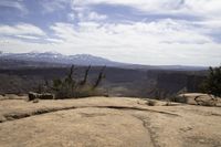 a small rock formation with view of some mountain ranges behind it in desert landscape with trees and shrubs