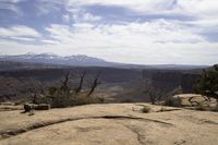a small rock formation with view of some mountain ranges behind it in desert landscape with trees and shrubs