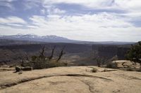 a small rock formation with view of some mountain ranges behind it in desert landscape with trees and shrubs