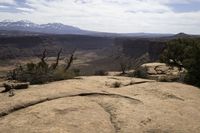 a small rock formation with view of some mountain ranges behind it in desert landscape with trees and shrubs