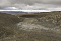 a mountain that has a dirt hill with no cars driving on it in it and some hills