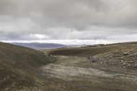 a mountain that has a dirt hill with no cars driving on it in it and some hills