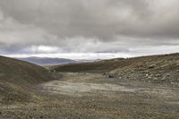 a mountain that has a dirt hill with no cars driving on it in it and some hills