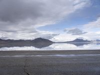 a road in the middle of nowhere is pictured in this photo with a mountain reflected on water