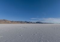 tracks in the sand leading into nowhere with mountains in the background with blue sky in a photograph