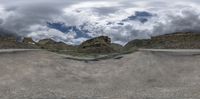 a skate park with lots of empty ramps and lots of mountains in the background and clouds