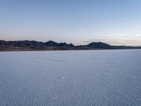 the vast empty landscape of an alien world where there are tracks in the snow and small clouds