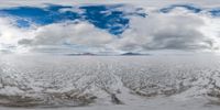 a panoramic image of a large field and snow capped mountain in the background